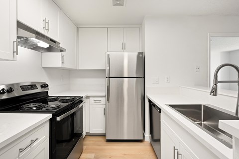 A modern kitchen with a stainless steel refrigerator and black countertops.