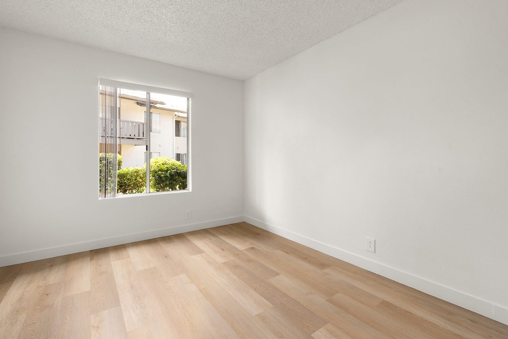 A room with a window and wooden flooring.