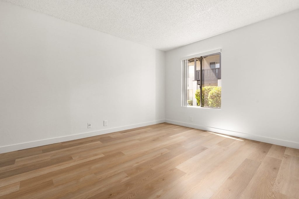 A room with wooden flooring and a window.