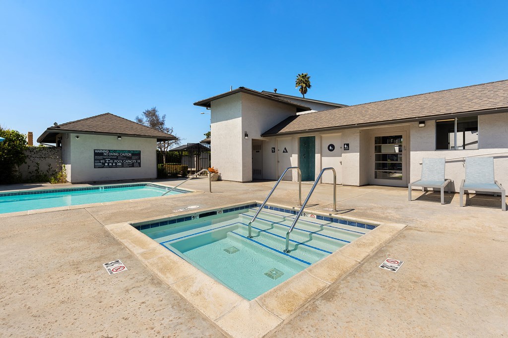 A pool with a diving board in front of a house.