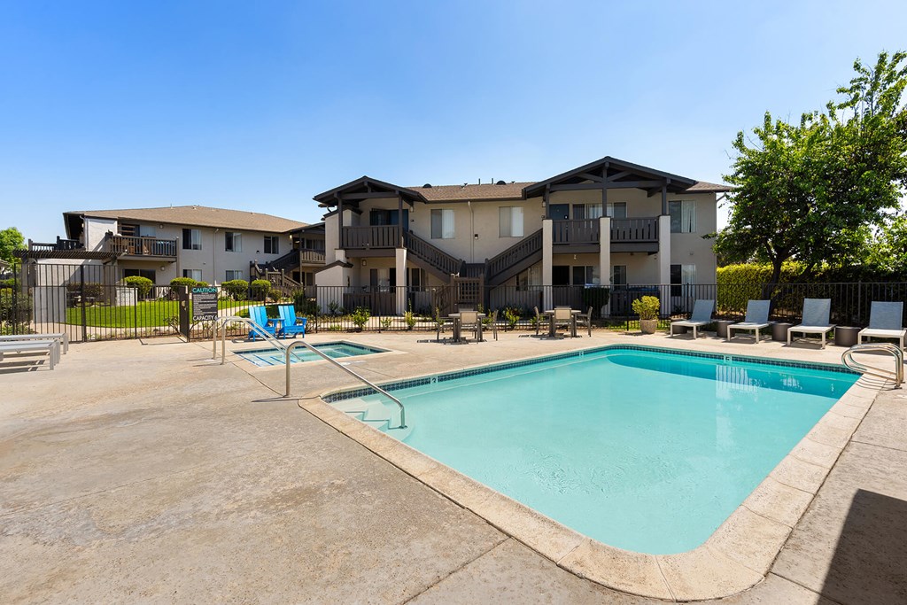 A large swimming pool in front of a multi-story apartment building.