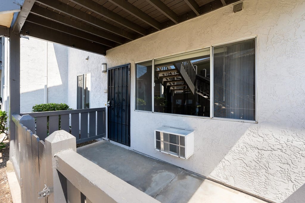 A white house with a black gate and a concrete staircase.