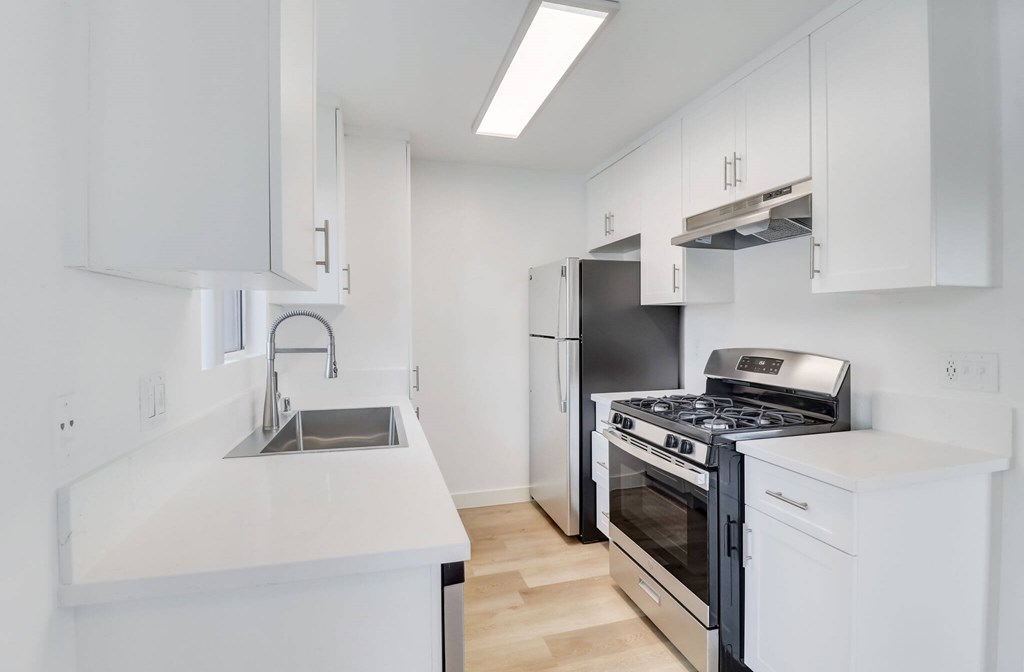 A modern kitchen with white cabinets and stainless steel appliances.