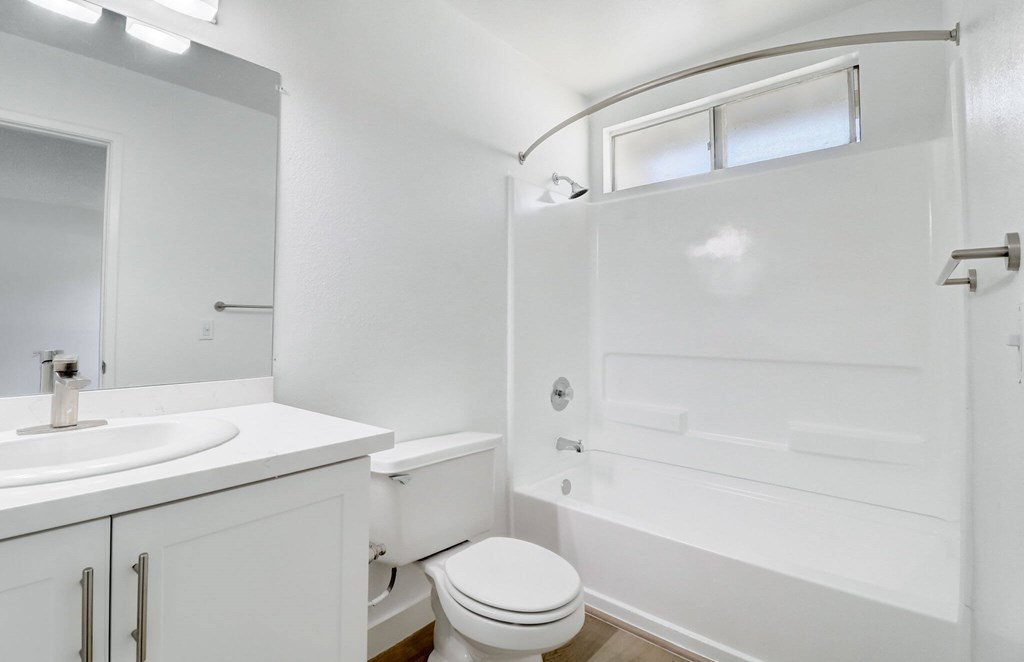 A white bathroom with a toilet, sink, and bathtub.