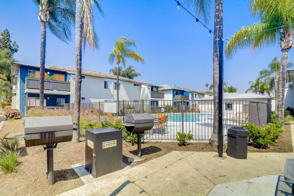 A sunny day at a residential area with palm trees and a pool.
