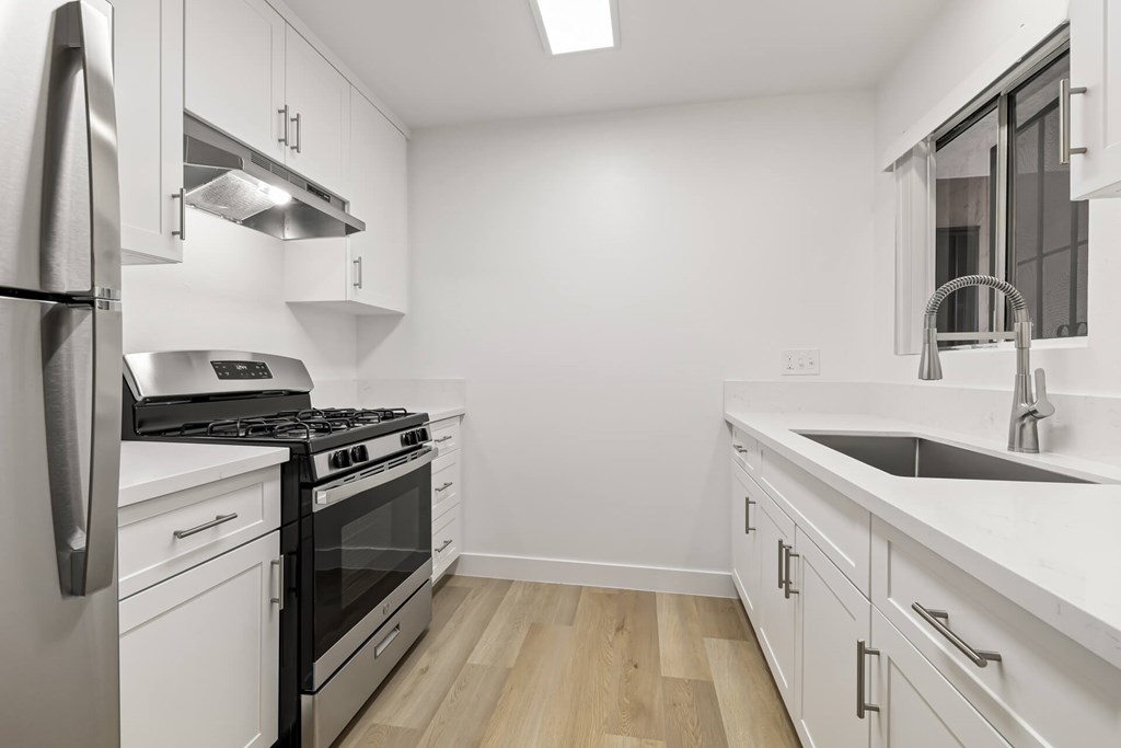 A modern kitchen with white cabinets and stainless steel appliances.