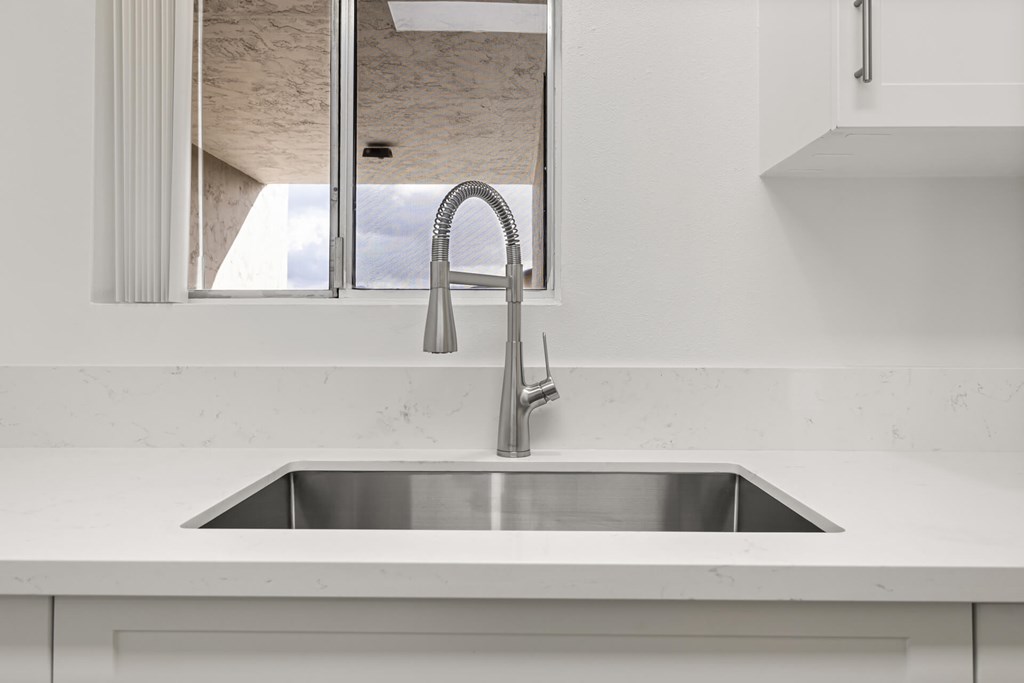 A modern kitchen sink with a chrome faucet.