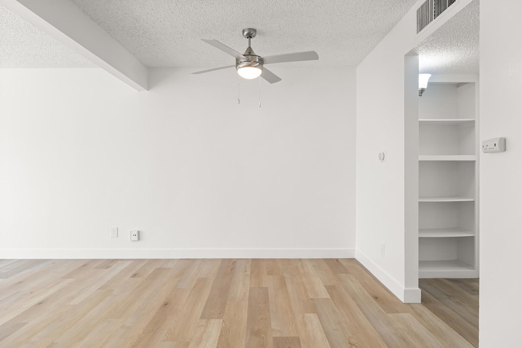 A room with a ceiling fan and wooden flooring.