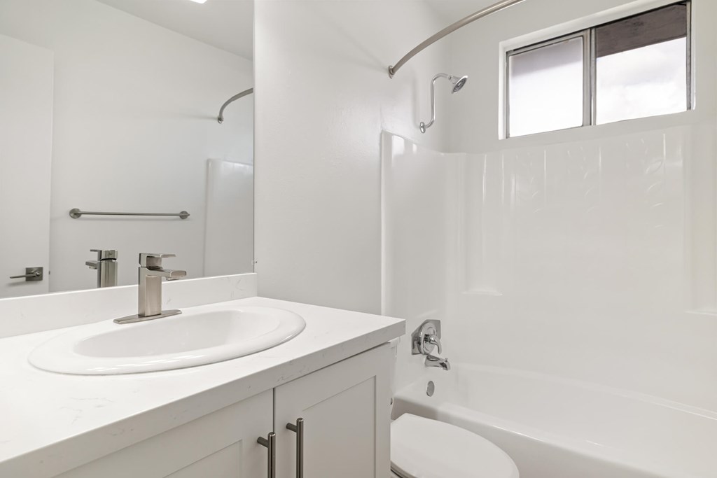 A white bathroom with a sink, toilet, and bathtub.