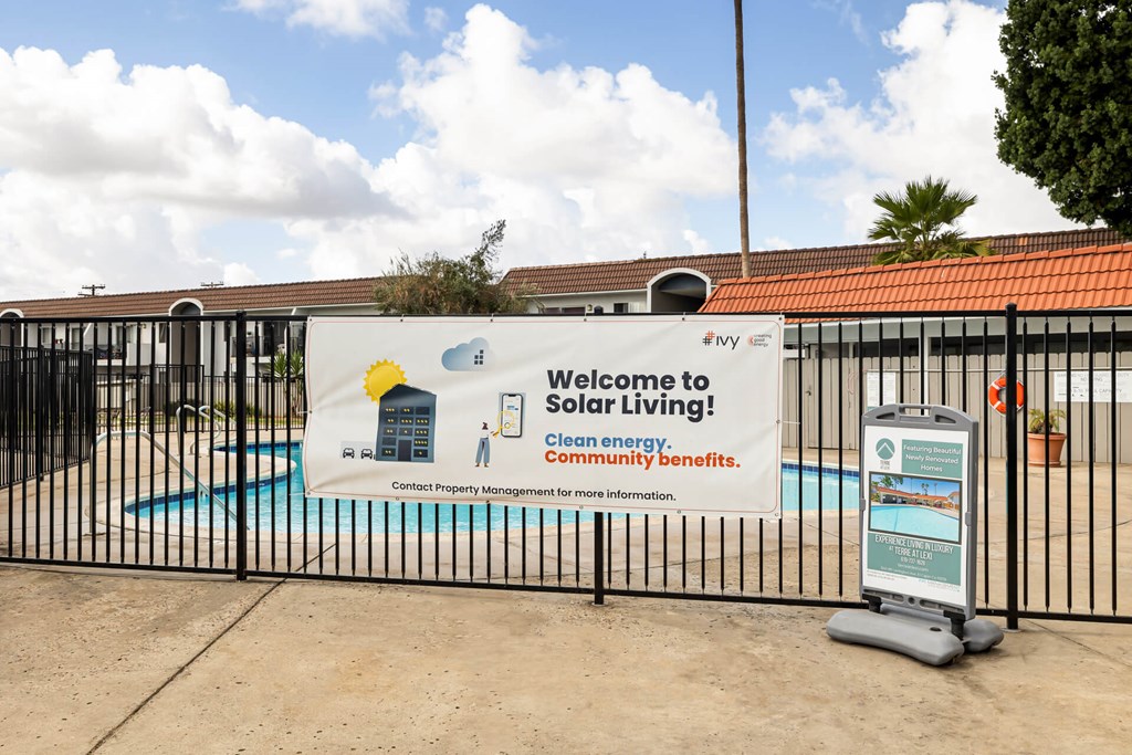 A sign welcoming people to Solar Living and a fence surrounding a pool.