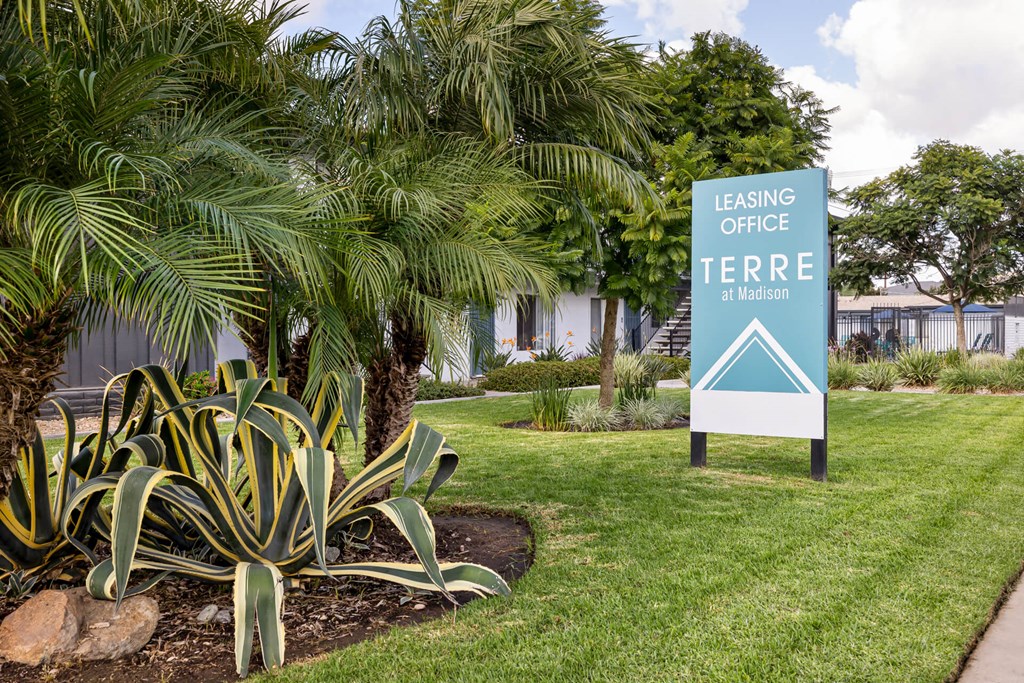 A sign for the Leasing Office at Terra Madison stands in a green lawn.