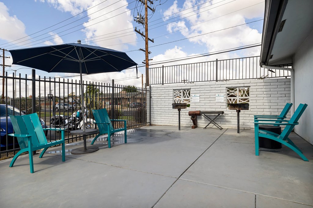 A patio with a blue umbrella and chairs.