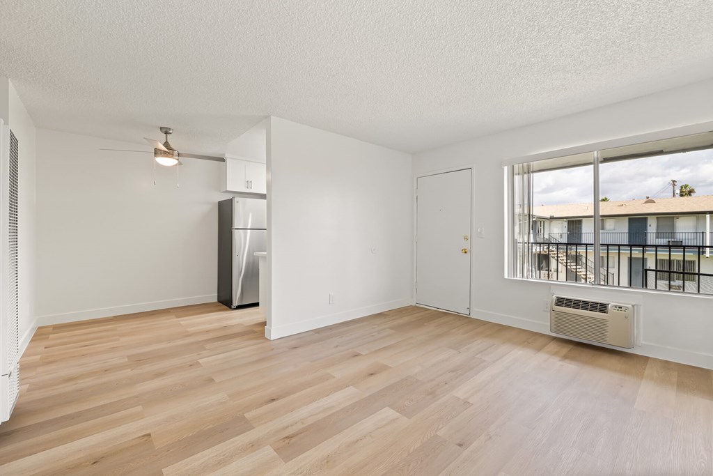 A spacious room with wooden flooring and a large window.