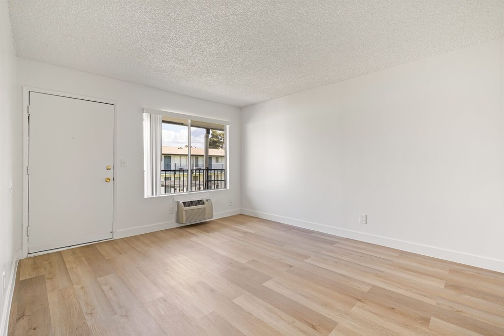 A room with a white door and a window with a view of a building outside.