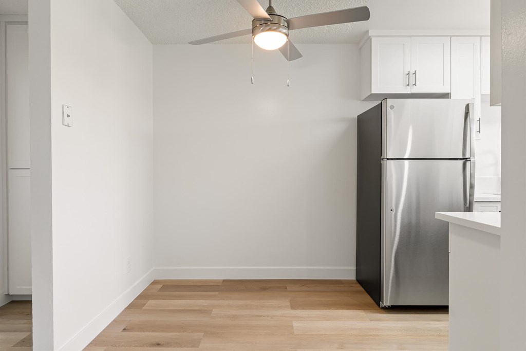 A kitchen with a refrigerator and a ceiling fan.