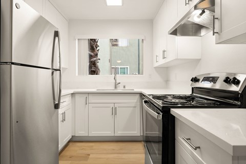 A modern kitchen with white cabinets and stainless steel appliances.