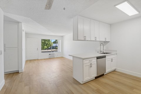 A kitchen with white cabinets and a window overlooking a green area.