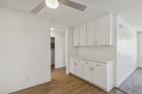 A kitchen with white cabinets and a ceiling fan.