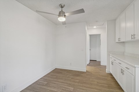 A room with a ceiling fan and wooden flooring.