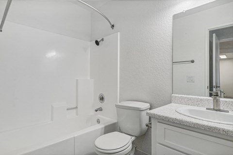 A white bathroom with a toilet, sink, and bathtub.