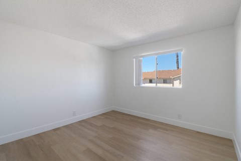 A room with a window and wooden flooring.