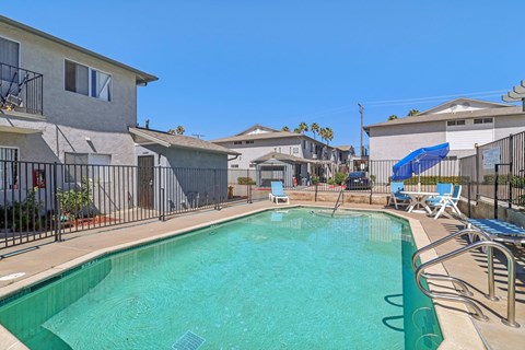 A swimming pool surrounded by a fence and chairs.
