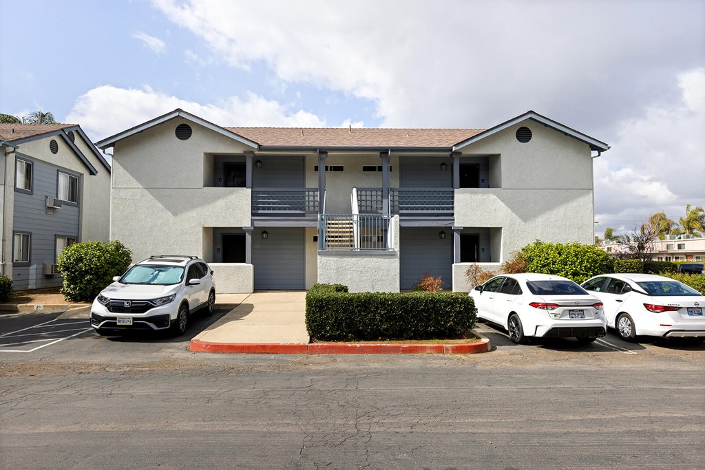 A white two-story building with a garage door and a car parked in front.