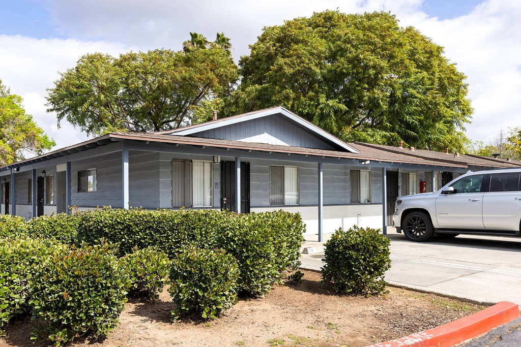 A grey house with a white car parked in front.