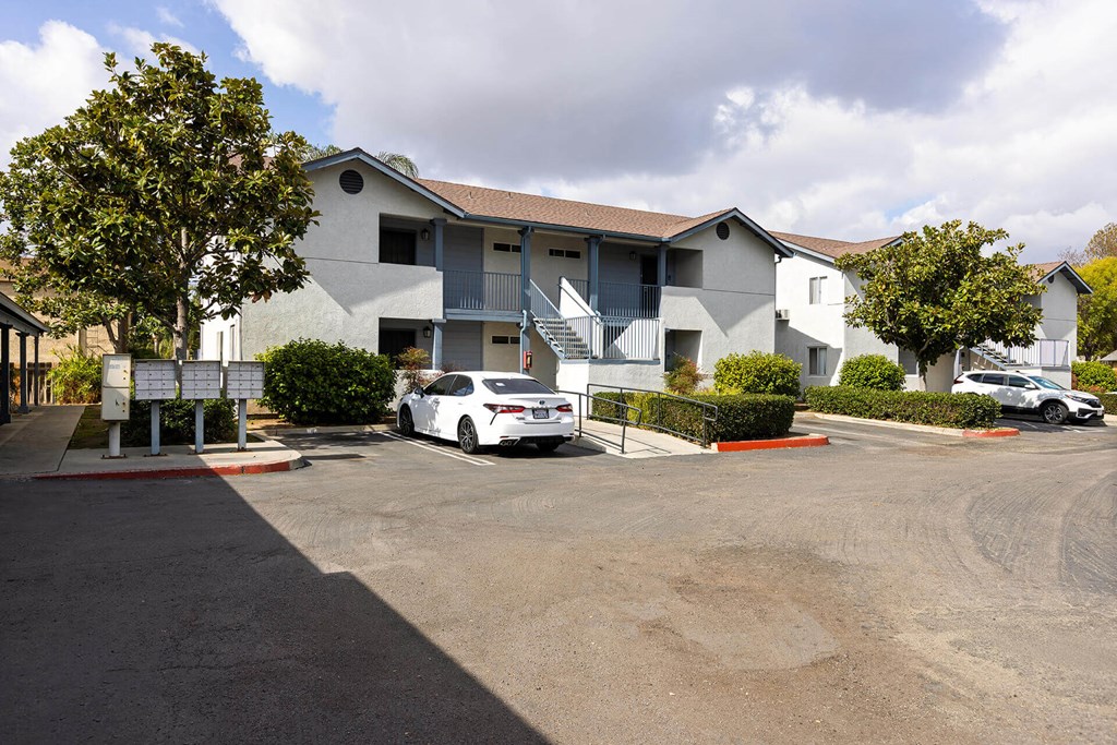A white car is parked in a parking lot in front of a building.