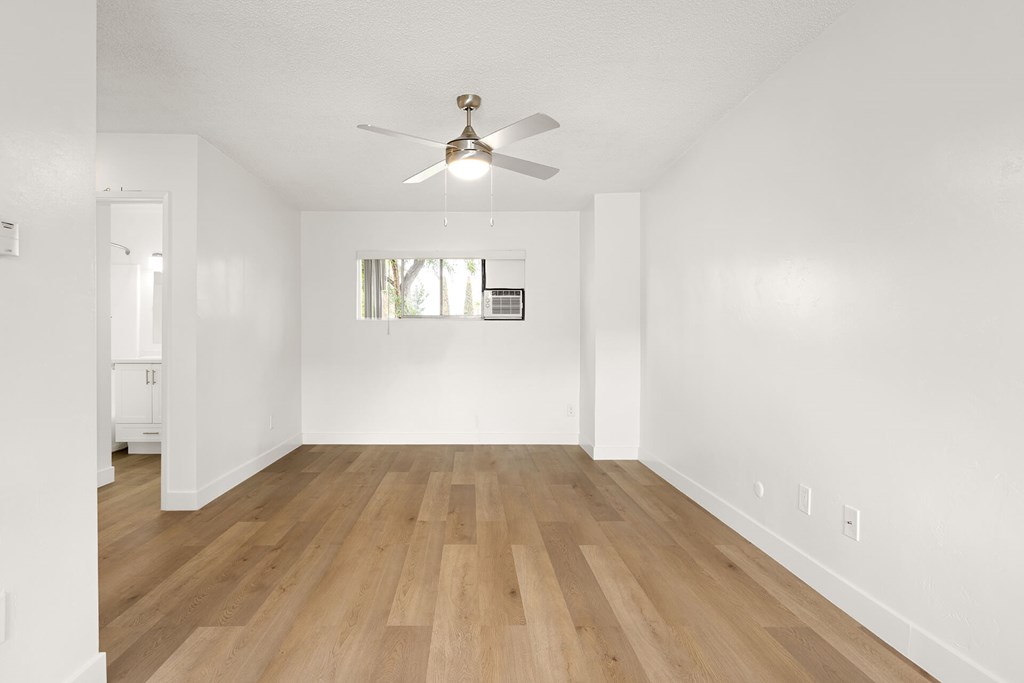 A room with a ceiling fan and wooden flooring.