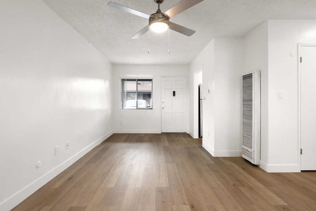 A room with a ceiling fan and wooden flooring.