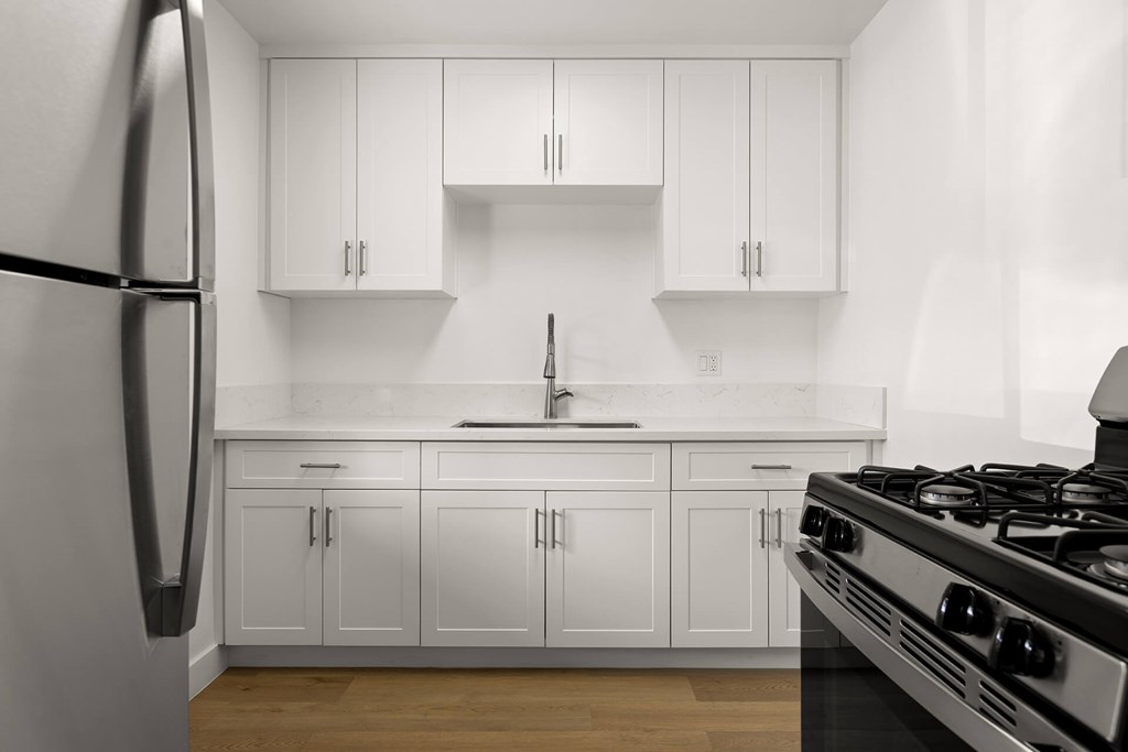 A modern kitchen with white cabinets and a stainless steel refrigerator.