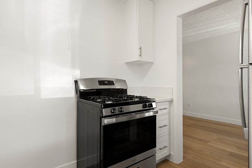 A black stove in a kitchen with white cabinets.