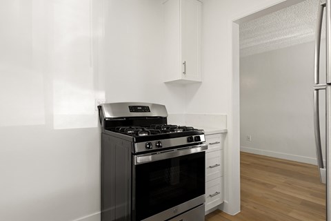 A black stove in a kitchen with white cabinets.