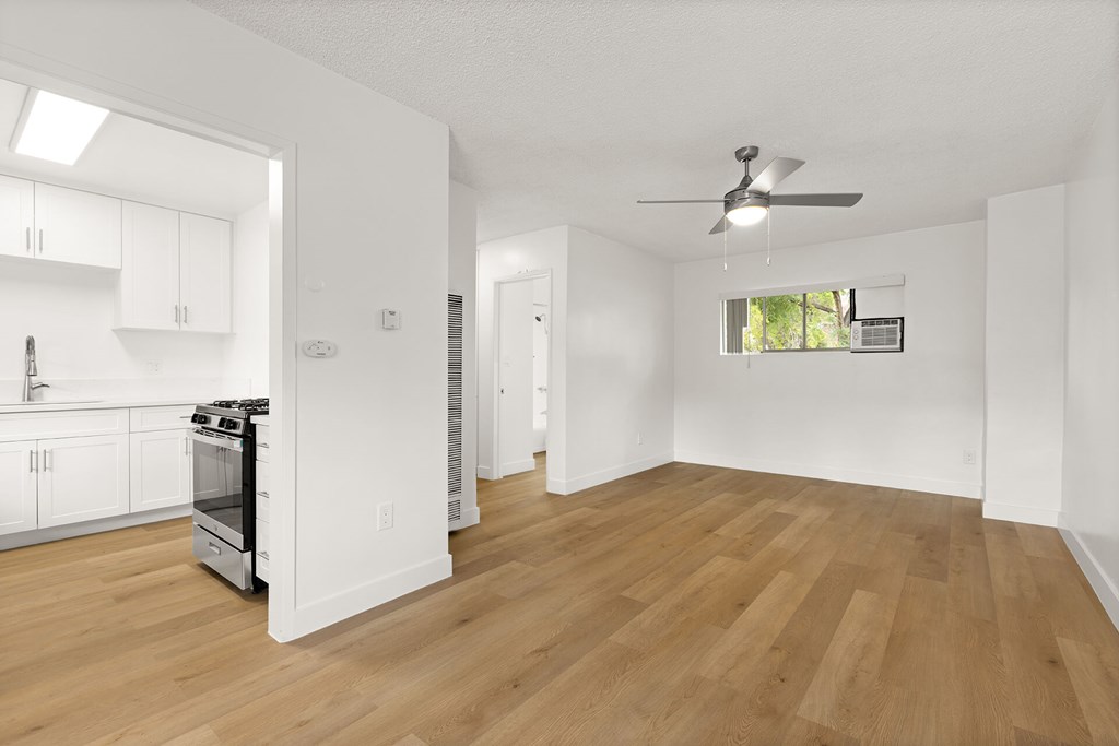 A spacious kitchen with wooden floors and white walls.