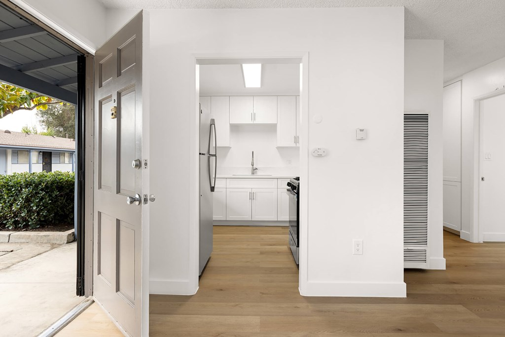 A white kitchen with a refrigerator, sink, and cabinets.