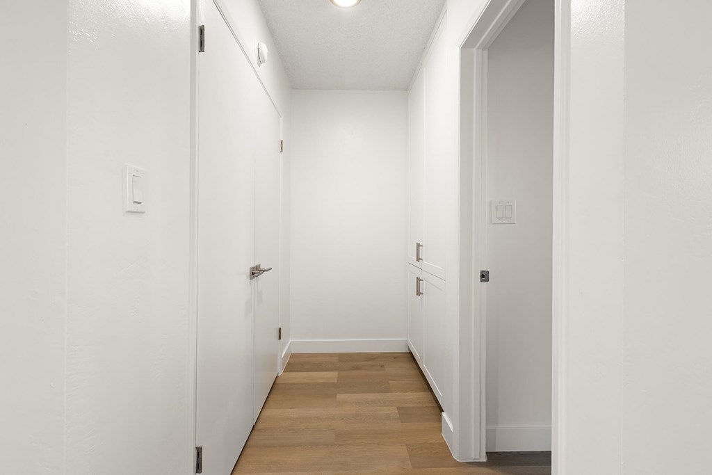 A long white hallway with a light on the ceiling.