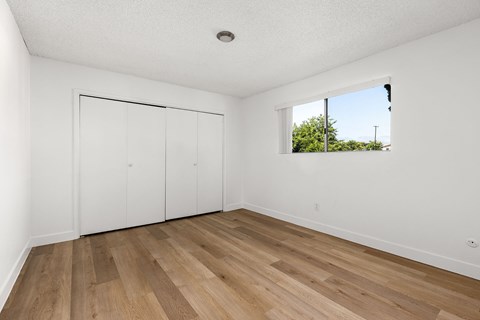 A room with a window and a wooden floor.