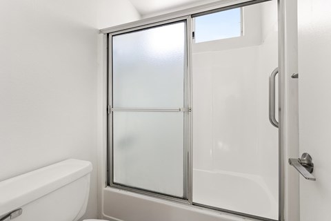 A white bathroom with a glass shower door.