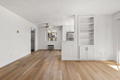 A kitchen with white cabinets and a wooden floor.