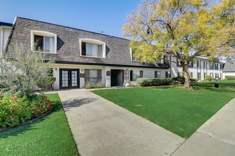 A building with a grey roof and a tree in front of it.