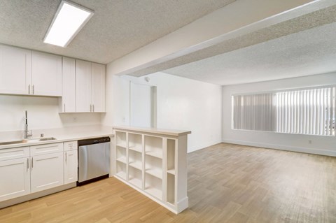 A kitchen with white cabinets and a wooden floor.