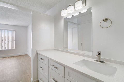 A bathroom with a sink, mirror, and lighting fixture.