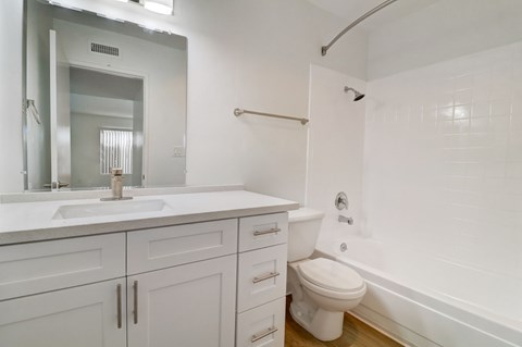 A white bathroom with a toilet, sink, and mirror.