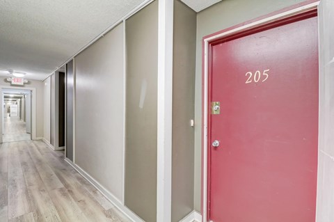 A hallway with a red door numbered 205.