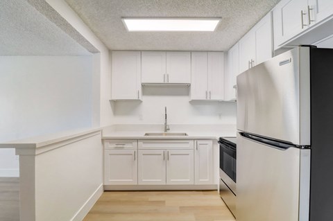 A kitchen with white cabinets and a black refrigerator.