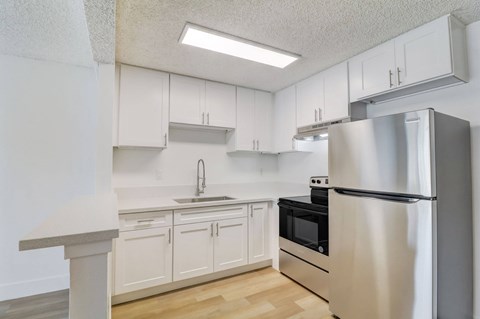 A kitchen with white cabinets and a stainless steel refrigerator.
