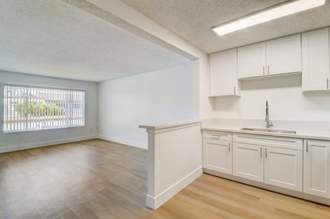 A kitchen with white cabinets and a window.