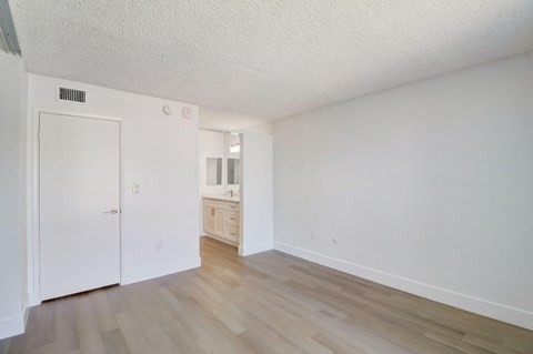 A white room with a wooden floor and a white door.