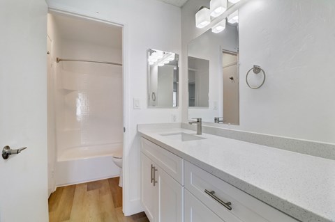 A white bathroom with a sink, mirror, and shower.